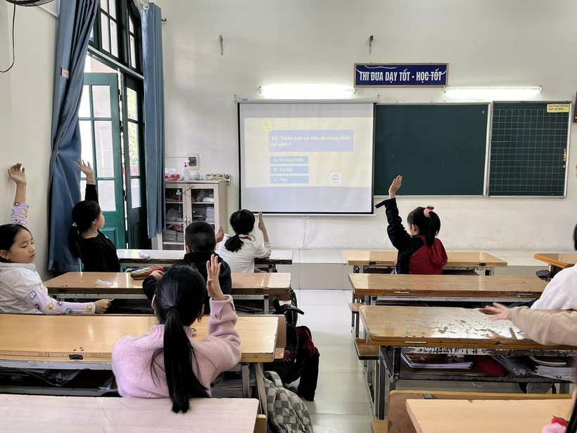 A group of students raising their hands in a classroom

Description automatically generated